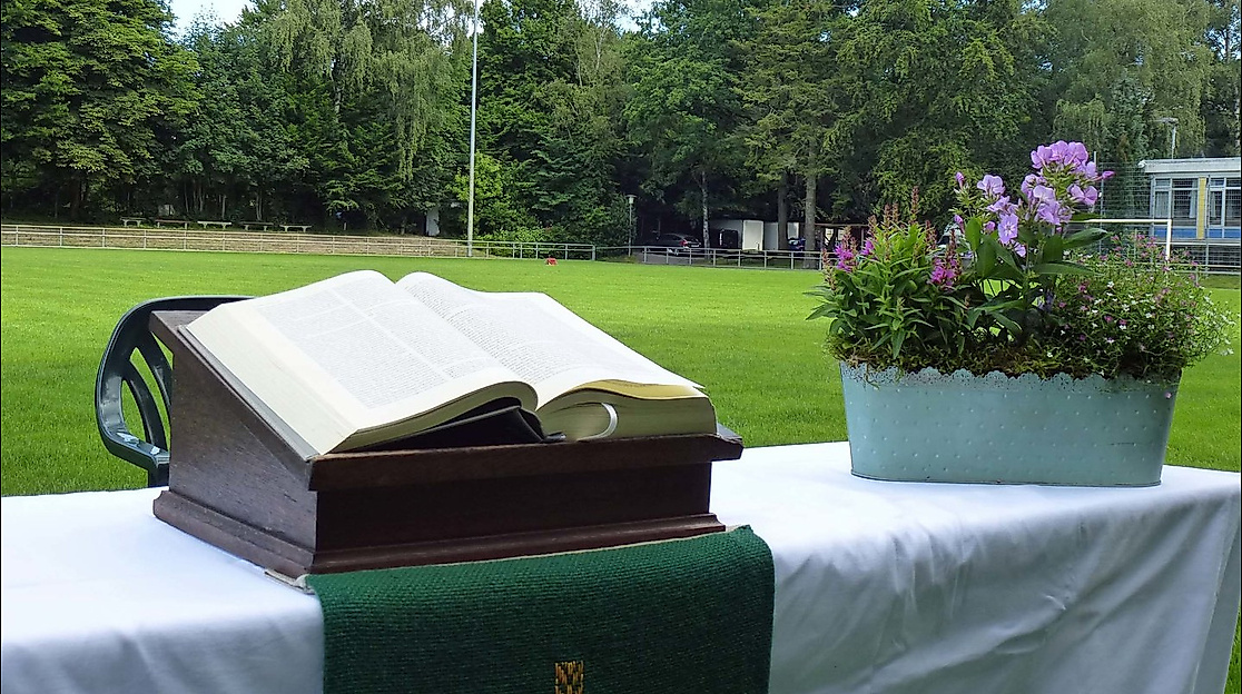 Aufgeschlagene Bibel und Blumenkorb auf einem Altar auf dem Fußballfeld