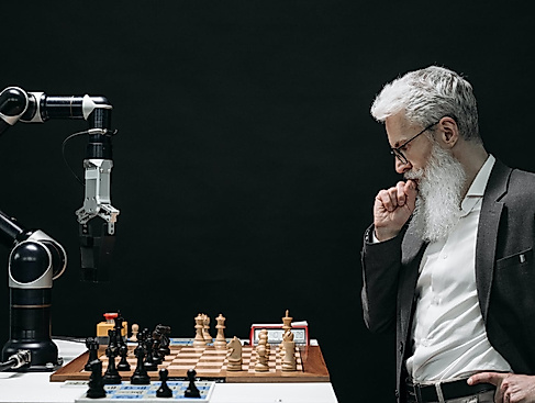 Ein Mann mit weißem Bart spielt Schach gegen einen Computer.