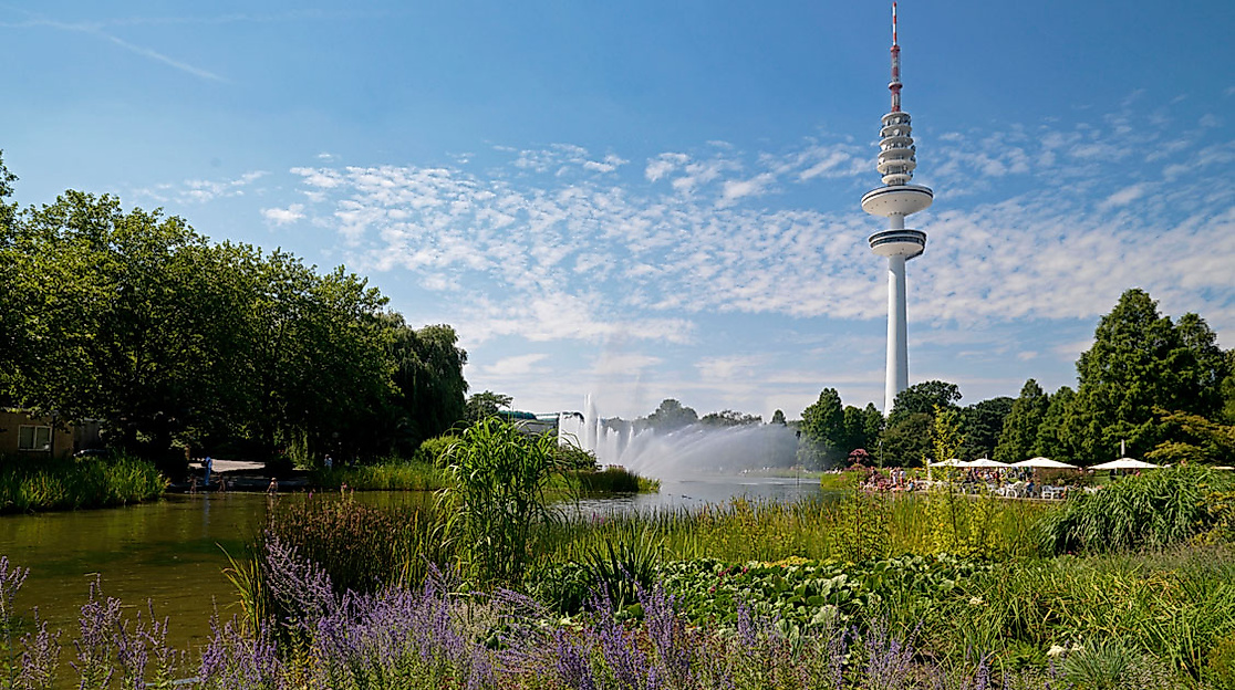 Blühende Uferlandschaft im Park Planten un Blomen mit Fernsehturm und Wasserfontäne im Hintergrund