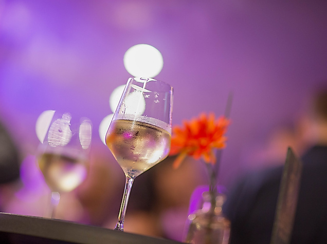 Weingläser und rote Blume auf Stehtisch bei stimmungsvoller Beleuchtung auf dem Winzerfest