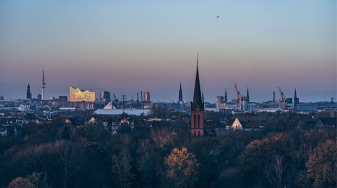 Blick vom Energiebunker Wilhelmsburg auf Hamburger Hafenkräne, Kirchtürme und Elbphilharmonie bei Abendlicht