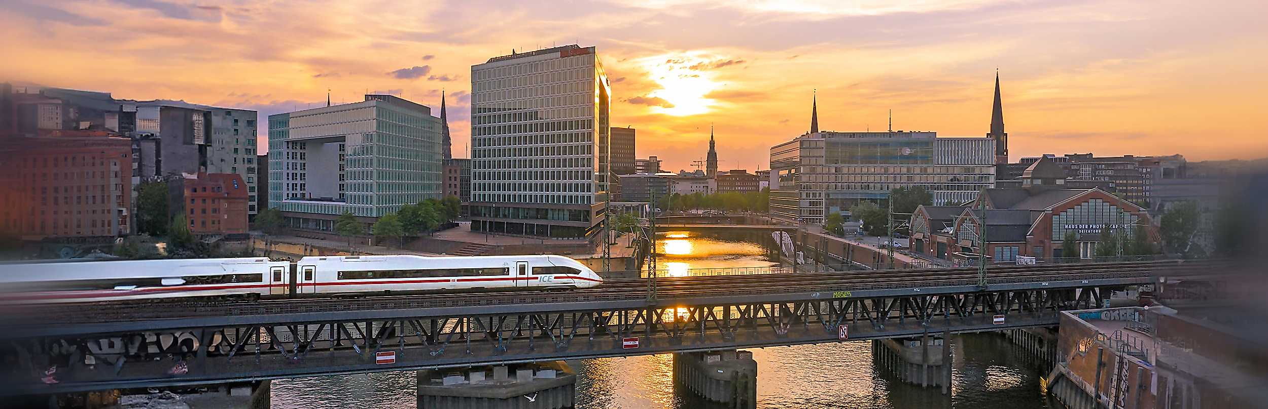 Einfahrender ICE bei Sonnenuntergang, im Hintergrund die Speicherstadt