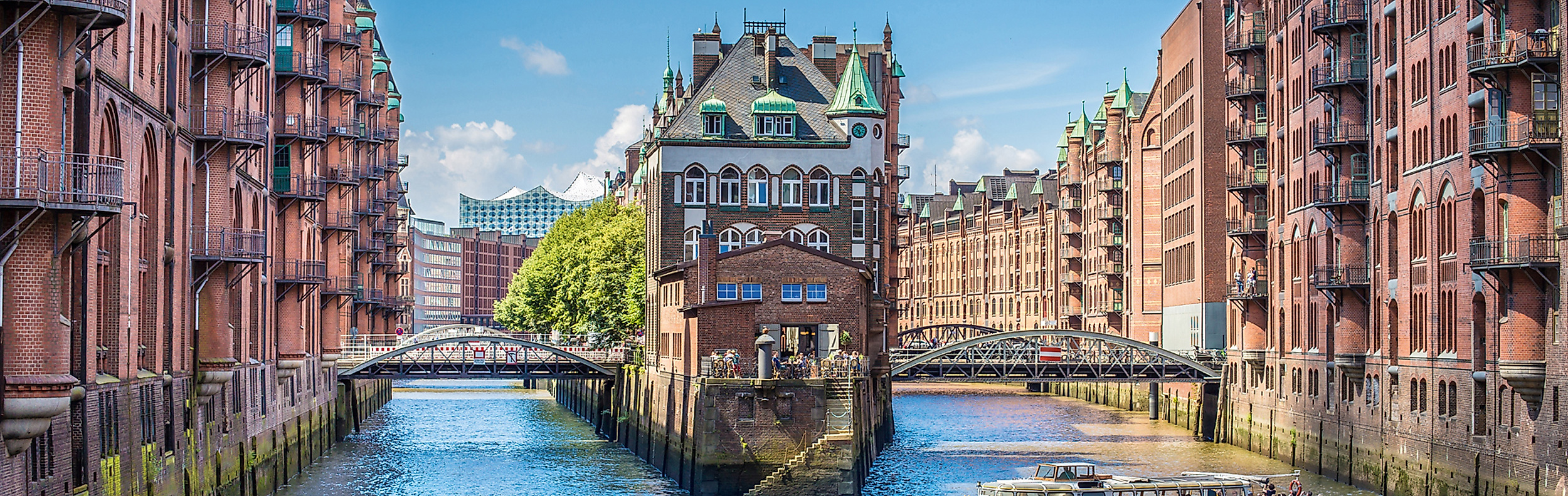 Historische Speicherstadt mit roten Backsteinfassaden und Kanalblick, Elbphilharmonie im Hintergrund.