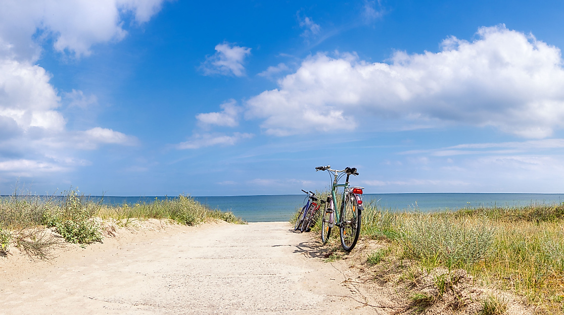 Sandweg mit Fahrrad durch die Dünen zum Meer bei Sonnenschein – Strandausflug ab Hamburg
