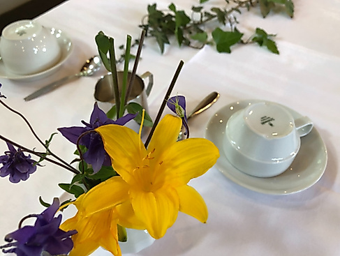 Ausschnitt Kaffeetafel: Umgedrehte Kaffeetassen und Blumenschmuck (Akelei und Taglilie)