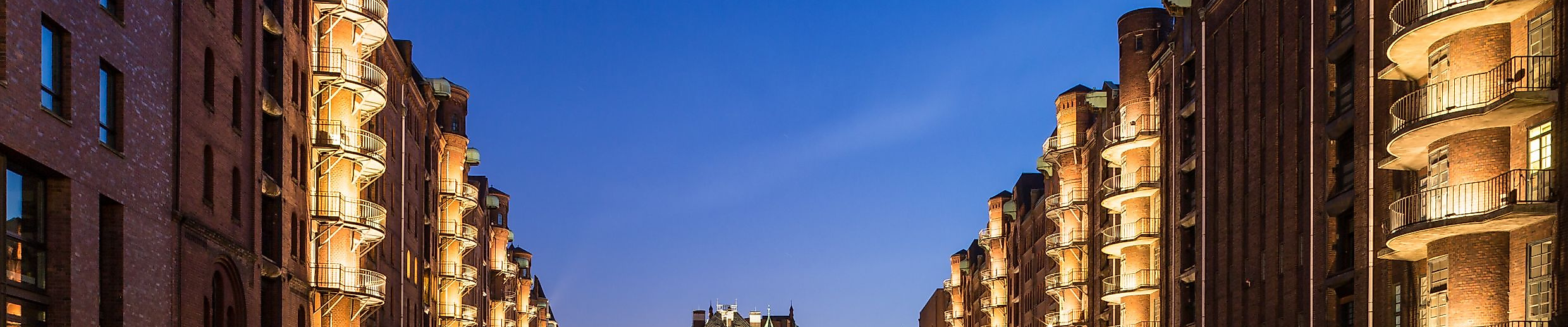 Beleuchtetes Wasserschloss in der Hamburger Speicherstadt bei Nacht, reflektiert im ruhigen Fleet