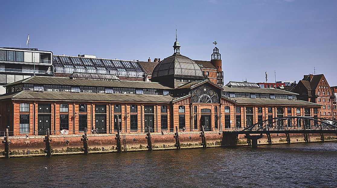 Außenansicht der Hamburger Fischauktionshalle mit rotem Klinkerbau am Ufer der Elbe bei Sonnenschein