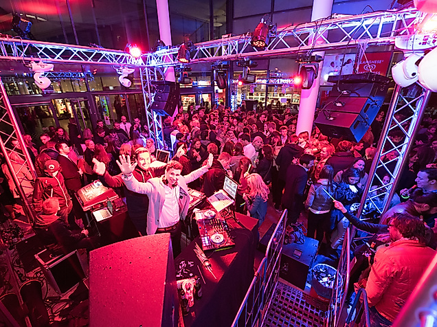 DJ-Pult mit Plattenspielern in der Sunset Lounge Disco, umgeben von buntem Licht und Partystimmung