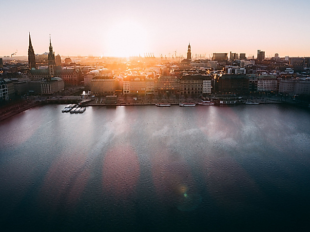 Panoramablick auf die Binnenalster bei Sonnenuntergang mit Kirchtürmen der Hamburger Altstadt.
