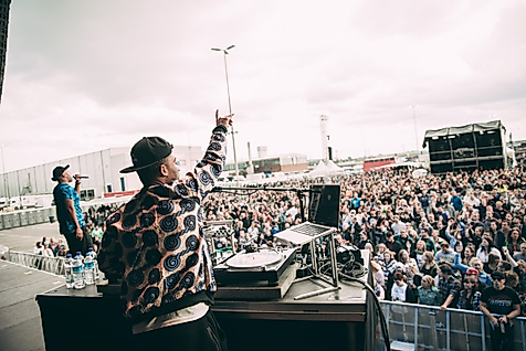 Beginner auf Festivalbühne vor tanzendem Publikum bei Open-Air-Event 