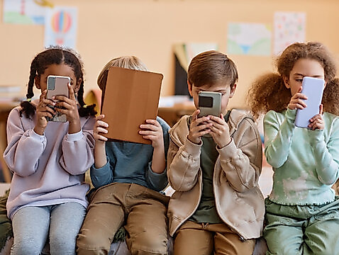 Group of young children holding smartphones and hiding faces, gen Alpha