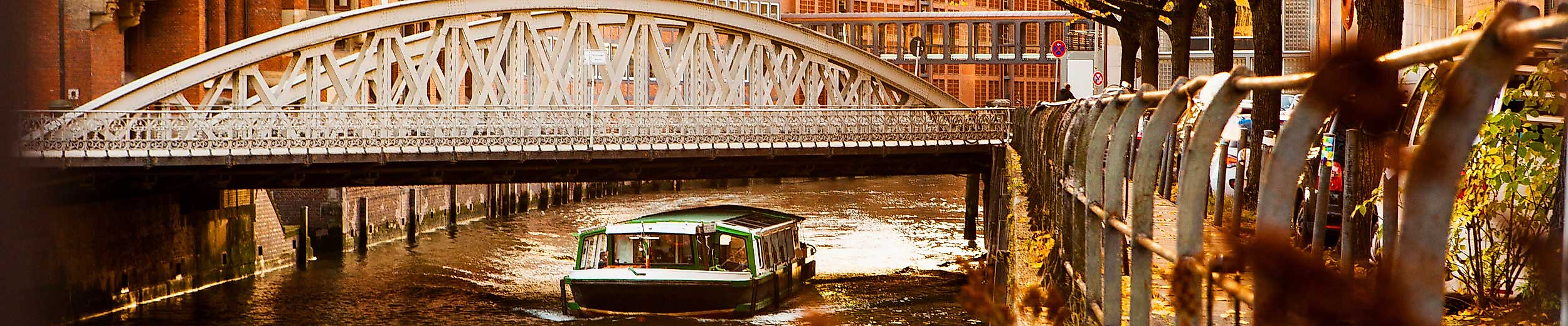 Sonnenlicht über Brücke in Hamburgs Speicherstadt mit Boot auf herbstlich gefärbtem Fleet.