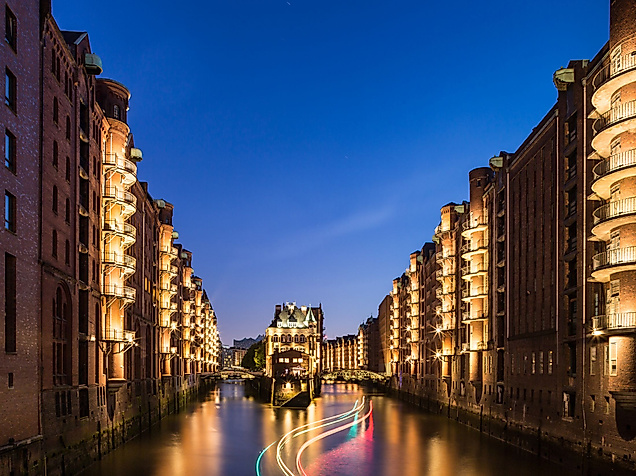 Beleuchtetes Wasserschloss in der Hamburger Speicherstadt bei Nacht, reflektiert im ruhigen Fleet