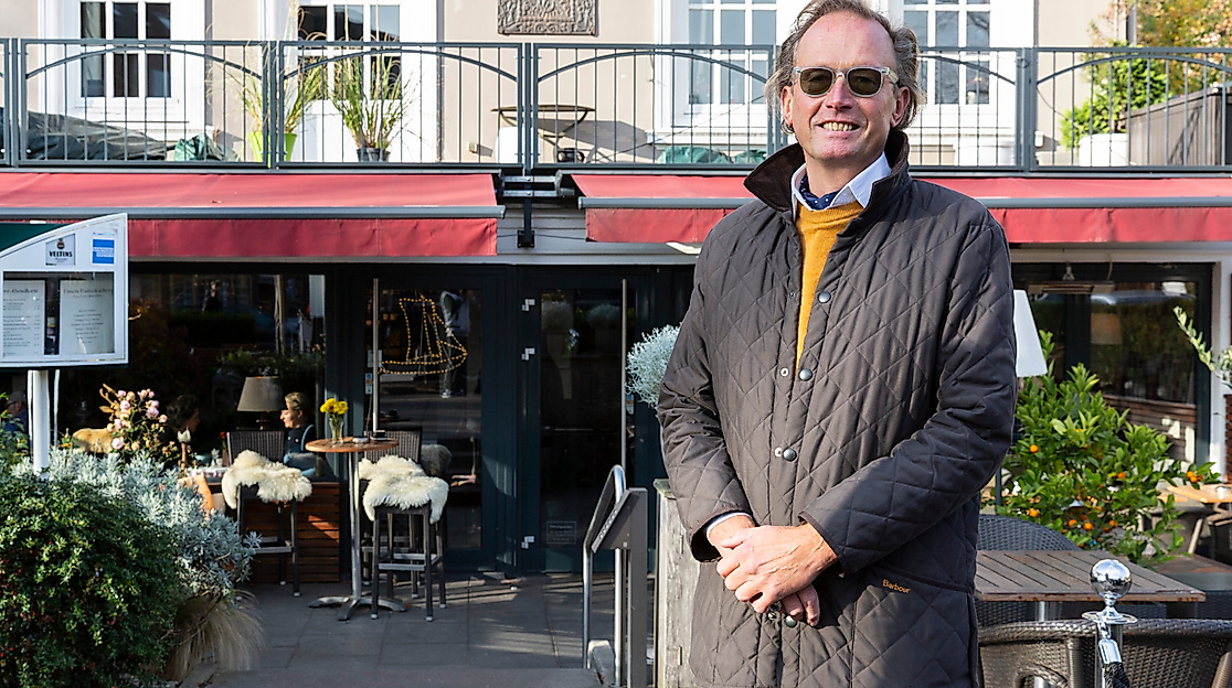 Andre Hallier mit Sonnenbrille vor Restaurantterrasse in Hamburg bei Sonnenschein