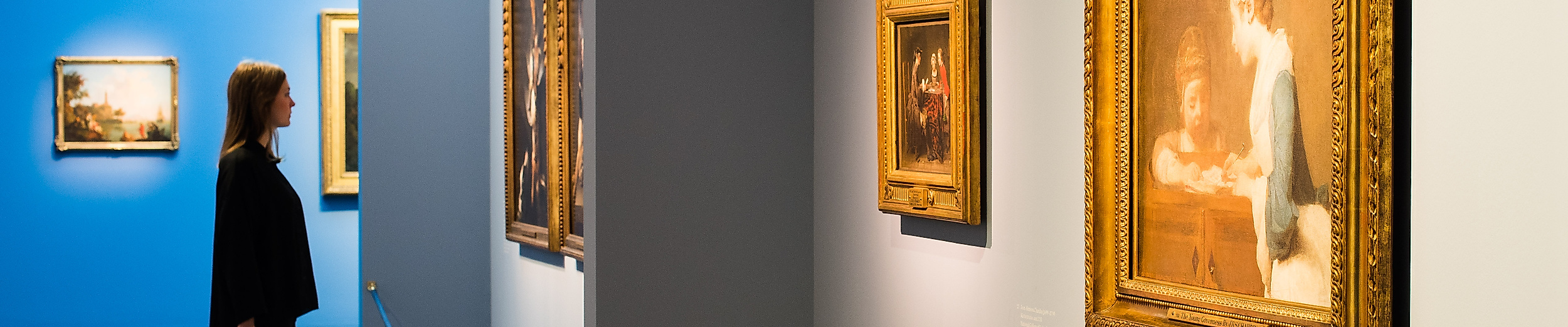 Besucher:in betrachtet Gemälde mit Goldrahmen in der Ausstellung „Die Farben Frankreichs“ in Hamburg 