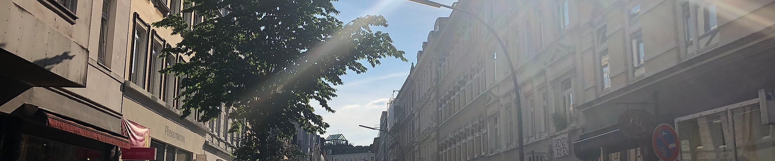 Sonnenlicht fällt auf die lebendige Bahrenfelder Straße mit kleinen Läden, Cafés und geparkten Fahrrädern