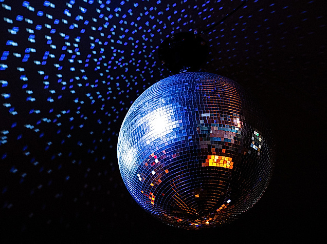 Leuchtende Discokugel reflektiert blaues und oranges Licht im dunklen Hamburger Club