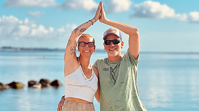 Frau und Mann bei Yoga am Strand von Scharbeutz und Haffkrug an der Ostsee in einer Yogaübung vor dem Meer