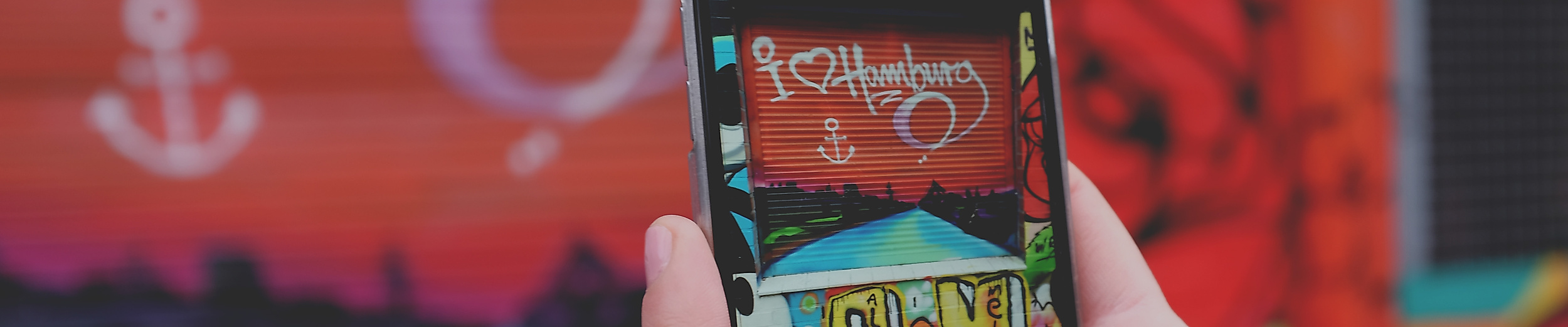 Smartphone fotografiert Hamburg-Graffiti mit Herz und Anker auf bunter Wand in St. Pauli