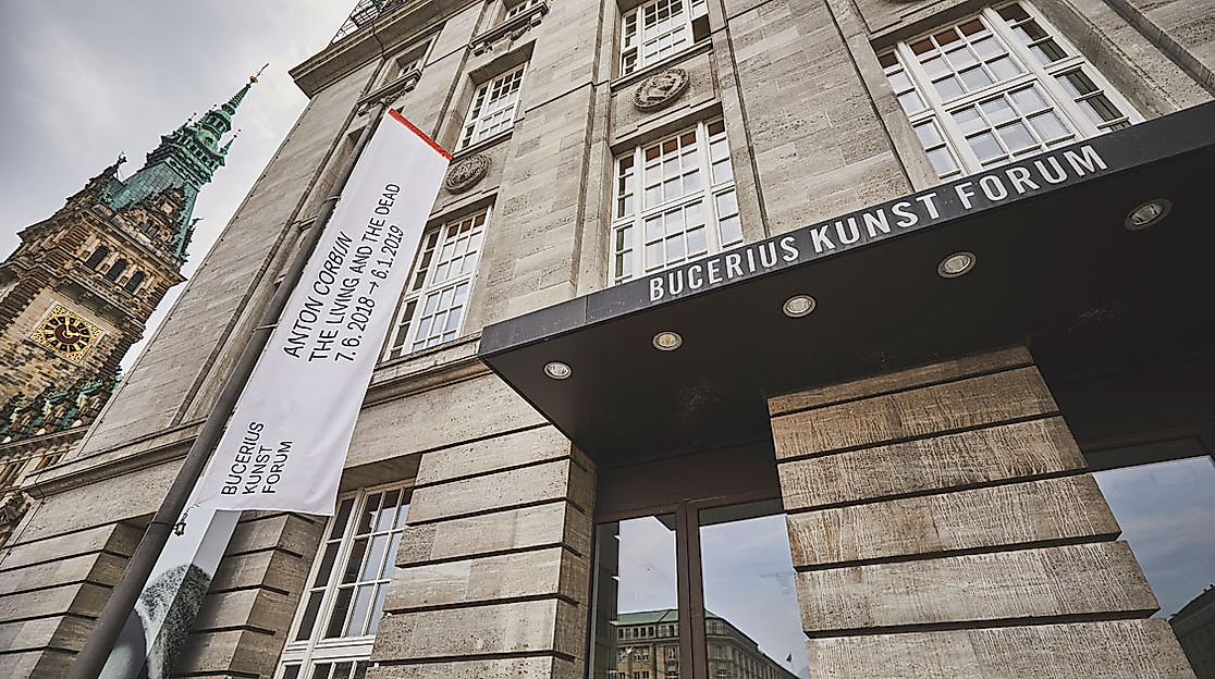 Blick auf das Bucerius Kunst Forum in Hamburg mit Banner, moderner Fassade und Rathausturm im Hintergrund