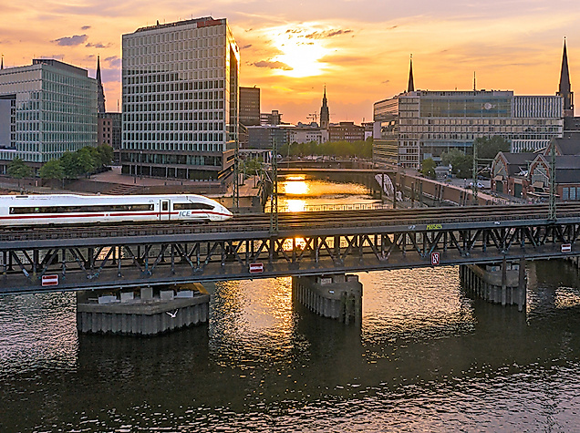 Einfahrender ICE bei Sonnenuntergang, im Hintergrund die Speicherstadt