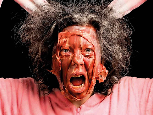 Eine Person mit zerzausten Haaren trägt ein rosa Hasenkostüm.
